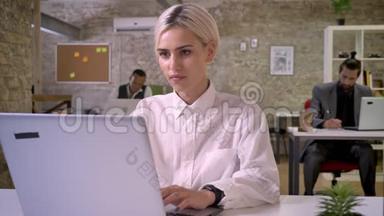 年轻快乐的女商人正在办公室里用笔记本电脑<strong>打字</strong>，同事们正在与技术、工作理念建立<strong>联系</strong>